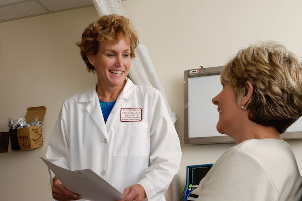 Medical professional in white lab coat consulting with patient - custom medical uniforms by WearUnify